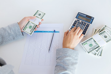 Image showing close up of hands counting money with calculator