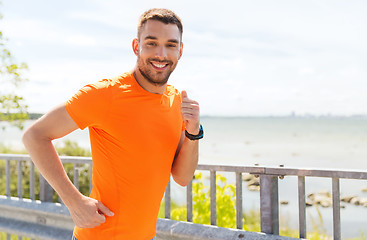 Image showing smiling young man running at summer seaside