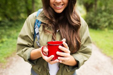 Image showing smiling young woman with cup and backpack hiking