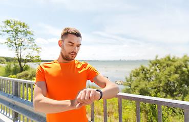 Image showing young man with smart wristwatch at seaside