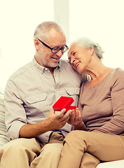 Image showing happy senior couple with red gift box at home