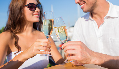 Image showing smiling couple clinking champagne glasses at cafe