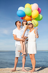 Image showing happy family with colorful balloons at seaside