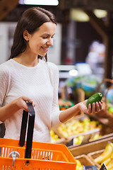 Image showing happy young woman with food basket in market