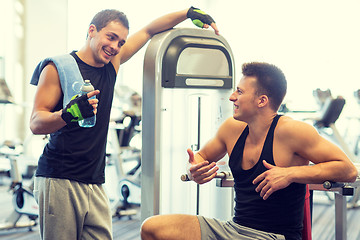 Image showing smiling men exercising on gym machine