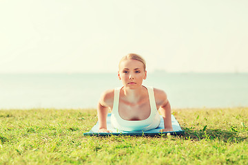 Image showing young woman making yoga exercises outdoors