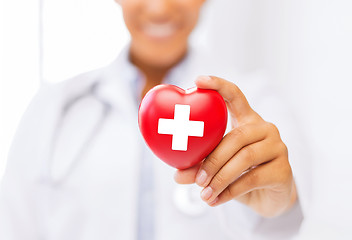 Image showing female doctor holding heart with red cross symbol