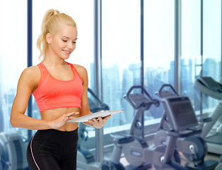 Image showing smiling sporty woman with tablet pc in gym