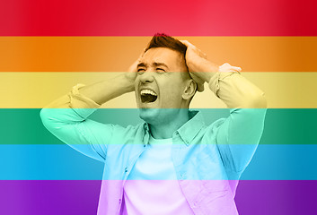 Image showing unhappy gay man shouting over rainbow flag