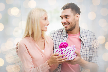 Image showing happy man giving woman gift box over lights