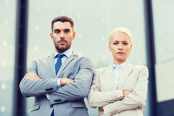 Image showing serious businessmen standing over office building