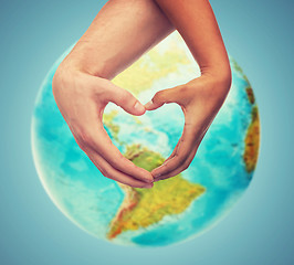 Image showing human hands showing heart shape over earth globe