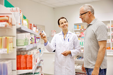 Image showing pharmacist showing drug to senior man at pharmacy