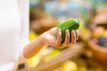 Image showing close up of woman hand holding avocado in market