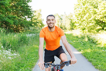 Image showing happy young man riding bicycle outdoors