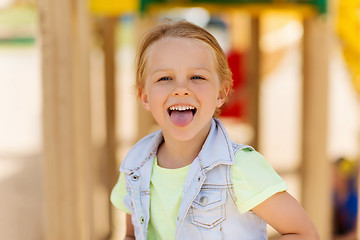 Image showing happy little girl showing tongue on playground