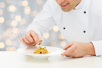 Image showing close up of happy male chef cook decorating dish