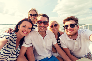 Image showing smiling friends sitting on yacht deck