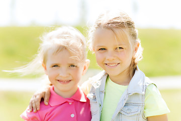 Image showing happy little girls hugging outdoors at summer