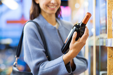 Image showing happy woman choosing and buying wine in market