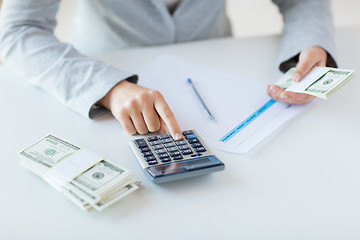 Image showing close up of hands counting money with calculator