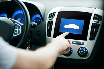 Image showing male hand pointing finger to car icon on panel