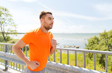 Image showing happy man with earphones running outdoors