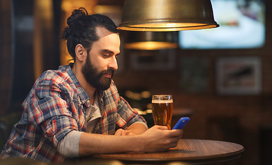 Image showing man with smartphone and beer texting at bar