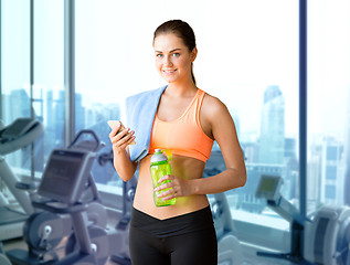 Image showing smiling sporty woman with smartphone in gym