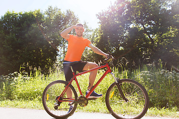 Image showing happy young man riding bicycle outdoors