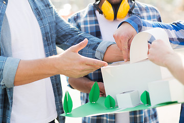 Image showing close up of builders with paper house model
