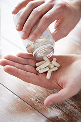 Image showing close up of man pouring pills from jar to hand
