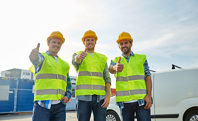 Image showing happy male builders in high visible vests outdoors