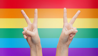 Image showing hands showing peace sign over rainbow stripes