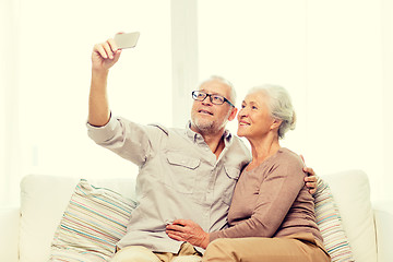 Image showing happy senior couple with smartphone at home