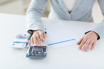 Image showing close up of hands counting money with calculator