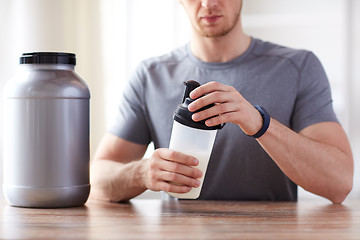 Image showing close up of man with protein shake bottle and jar