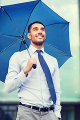 Image showing young smiling businessman with umbrella outdoors