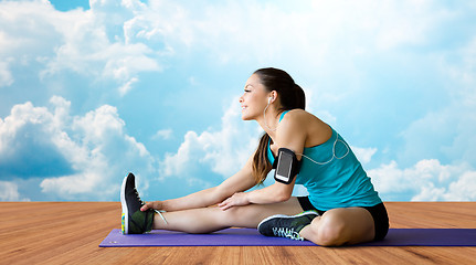 Image showing smiling woman stretching leg on mat over clouds