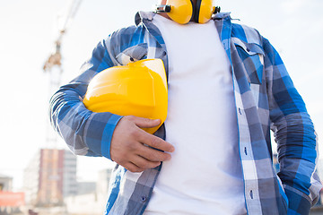 Image showing close up of builder holding hardhat on building