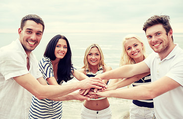 Image showing smiling friends putting hands on top of each other