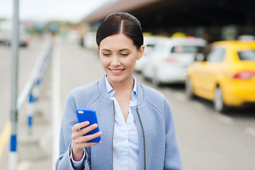 Image showing smiling woman with smartphone over taxi in city