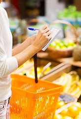 Image showing close up of woman writing to notepad in market