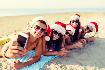 Image showing group of friends in santa hats with smartphone