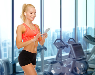 Image showing smiling sporty woman with smartphone and earphones