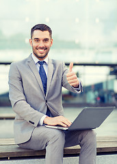 Image showing smiling businessman working with laptop outdoors