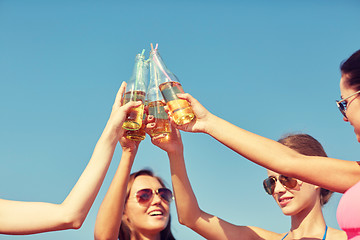 Image showing close up of happy young women clinking bottles