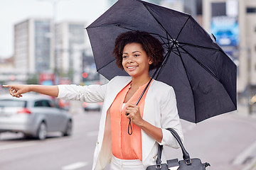 Image showing happy african woman with umbrella catching taxi