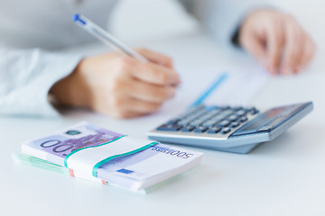 Image showing close up of hands counting money with calculator