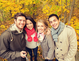 Image showing smiling friends taking selfie in autumn park